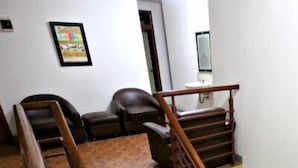 A hallway with a staircase, a brown leather sofa, and a framed picture on the wall. - De Sun Pasteur Guest House by HouseinBandung (Bandung)