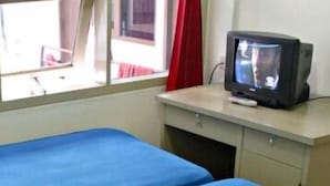 A small room with a single bed, a desk with a television, and a window with a view of the outside. - De Sun Pasteur Guest House by HouseinBandung (Bandung)