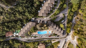 Luchtbeeld van een woongebied met meerdere huizen, een zwembad en een parkeerplaats.