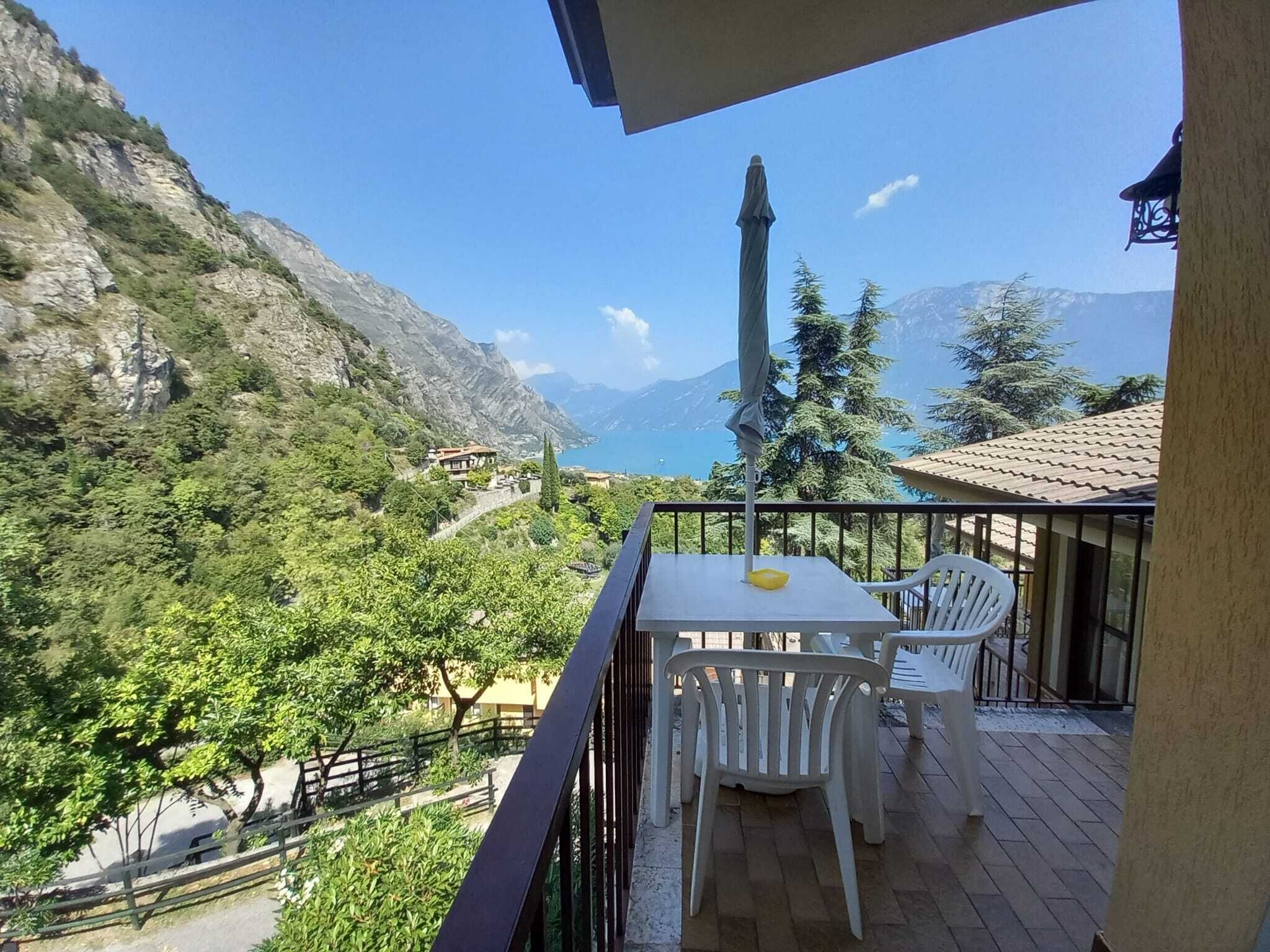 Een balkon met tafel en stoelen, uitzicht op een bergachtig landschap met een zeezicht.