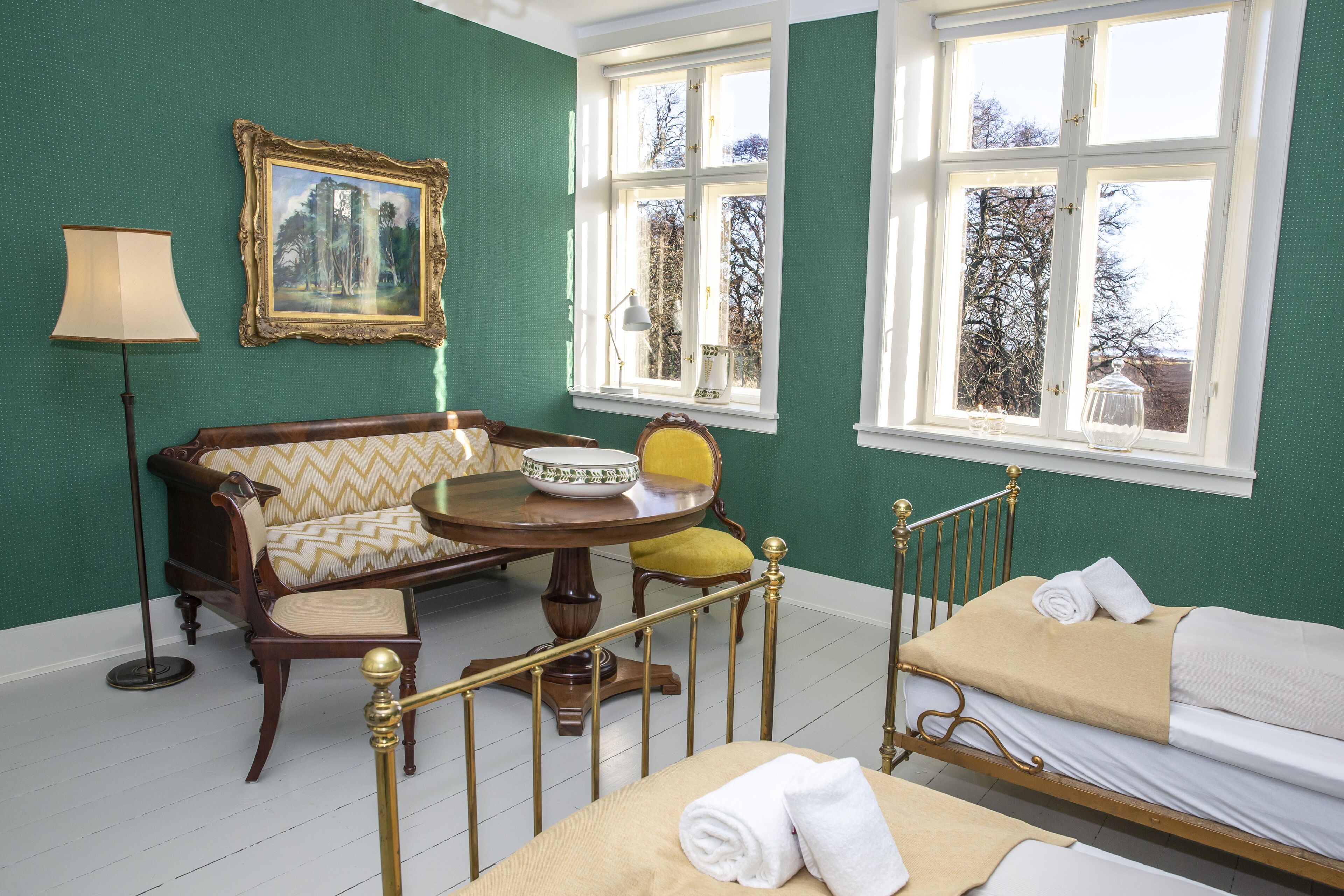 A room with a bed, a sofa, a table with a bowl, and a lamp.