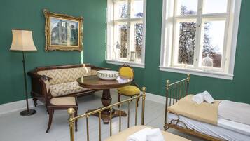 A room with a bed, a sofa, a table with a bowl, and a lamp.