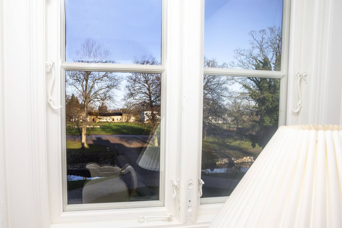 A room with a large window offering a view of a park and a building.
