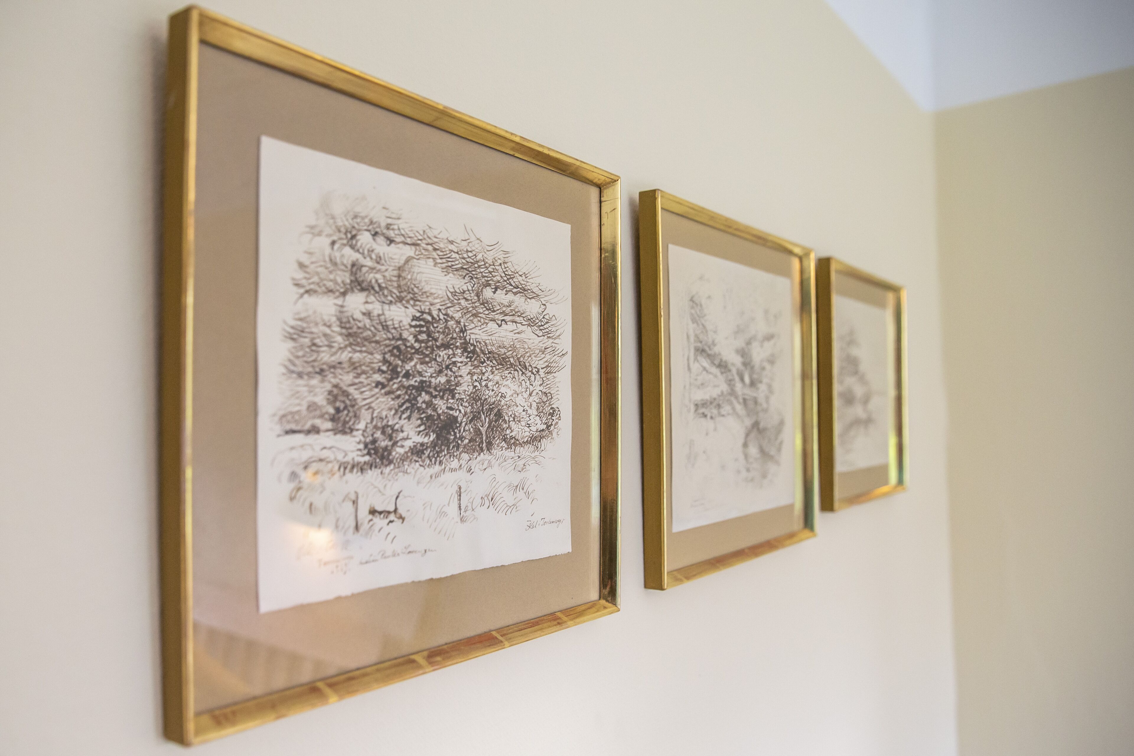 Three framed black and white sketches on a wall.