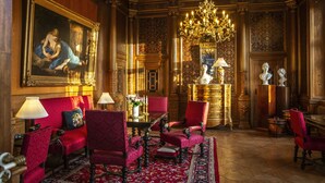 A luxurious room with a red upholstered sofa, matching armchairs, a chandelier, and a large painting on the wall. - Fuglsang Herregaard Hotel (Toreby)