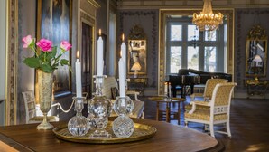 A room with a piano, ornate vases, and a chandelier. - Fuglsang Herregaard Hotel (Toreby)