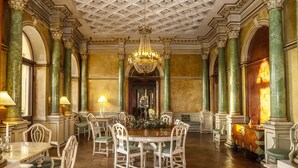 A grand dining room with a chandelier, ornate columns, and a central table surrounded by chairs. - Fuglsang Herregaard Hotel (Toreby)
