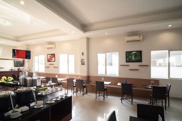 A spacious dining area with multiple tables and chairs, a coffee station, and large windows providing natural light. - Midtown Xpress Sampit Kalimantan Tengah (Sampit)