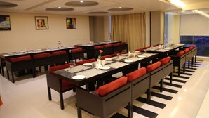A conference room with long tables, red cushioned chairs, and a modern ceiling design.