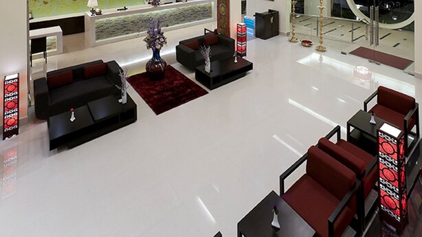 A spacious lobby with a reception desk, seating areas, and a high ceiling with chandeliers.