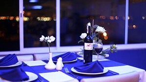 Una tavola imbandita per due, con una bottiglia di vino, un bicchiere e un vaso di fiori.
