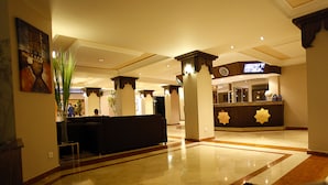 Una hall con una reception, un divano e una pianta grande.
