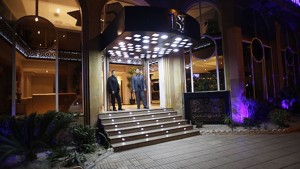 Ingresso di un hotel con gradini illuminati e due manichini in abito formale.