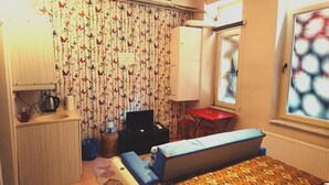 A compact room with a bed, a small table, a chair, a TV, and a window with a view of buildings. - Golden Galata Hotel (Istanbul)
