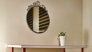 A small, white table with red legs, a round mirror with a black frame, and a white vase with a plant on top. - Golden Galata Hotel (Istanbul)