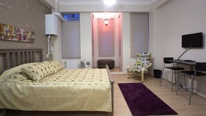 A bedroom with a bed, a desk, a chair, a radiator, a TV, and a window. - Golden Galata Hotel (Istanbul)