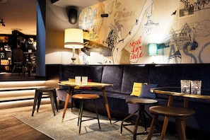 A cozy bar area with a sofa, tables, and a mural.