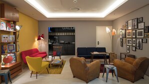 Een moderne woonkamer met een bank, fauteuils, een salontafel en een boekenkast.
