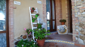 A building entrance with a brick facade, a white door, and a stone wall. There are signs reading "Panorea" and "Stormhell". - Villa Quiete (Spadafora)