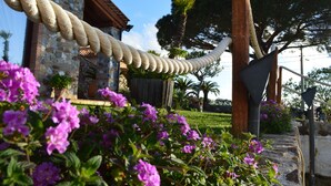 A rope bridge over a stone wall, with a building and trees in the background. - Villa Quiete (Spadafora)