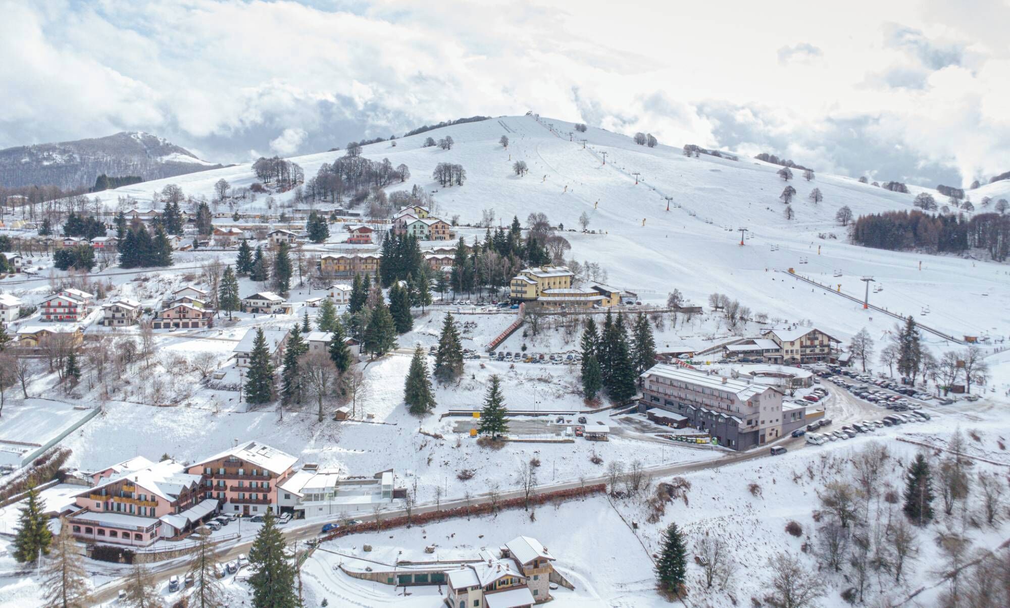 Eine verschneite Stadt mit Häusern, einer Skipiste und einer Straße.