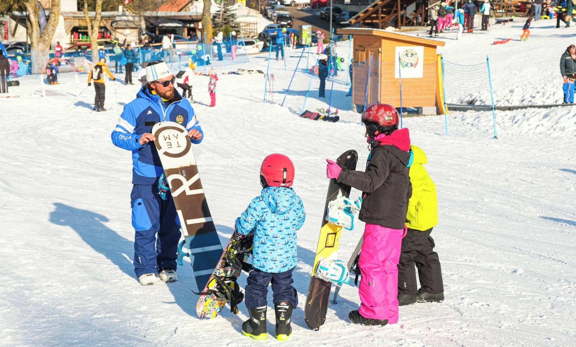Area innevata all'aperto con persone e snowboard.
