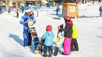 Area innevata all'aperto con persone e snowboard.