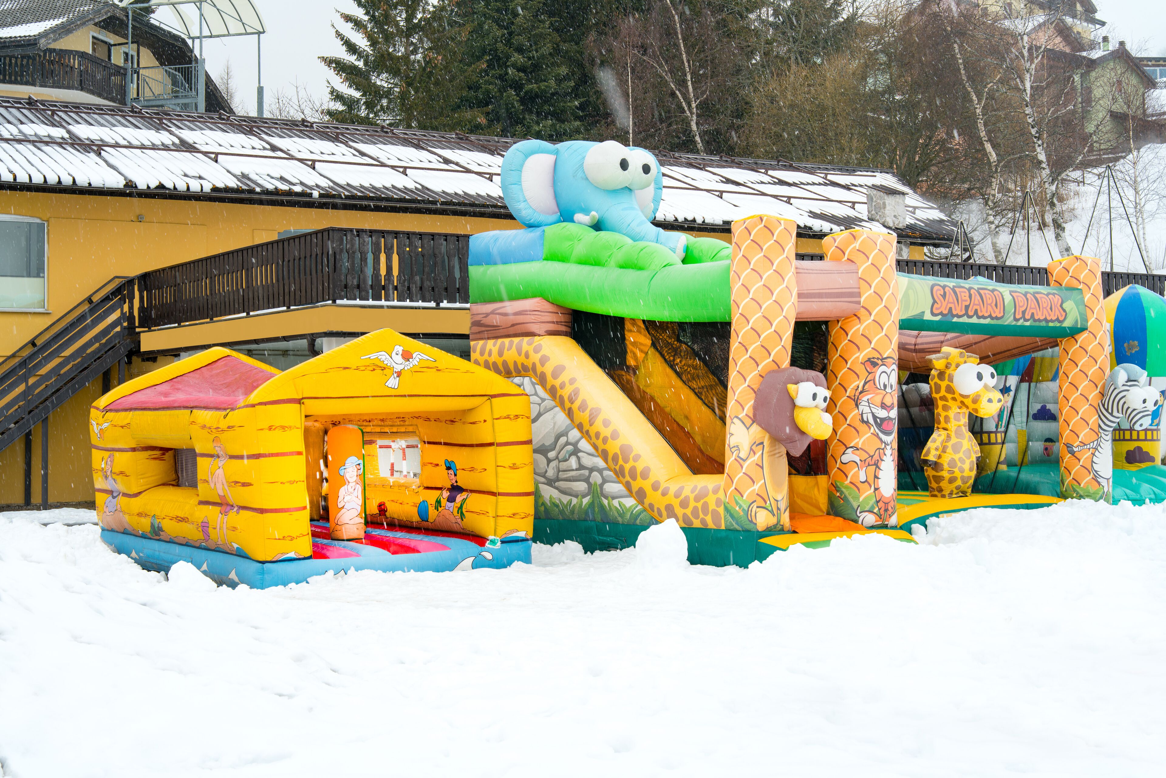En snötäckt uppblåsbar lekplats med djurfigurer och en skylt med texten ”Safari Park”.