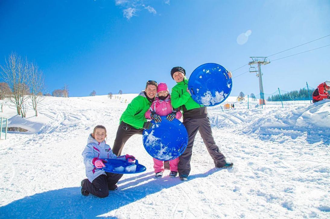A snowy outdoor area with people holding snowboards.