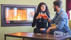 Twee personen zitten aan een tafel met uitzicht op een open haard.