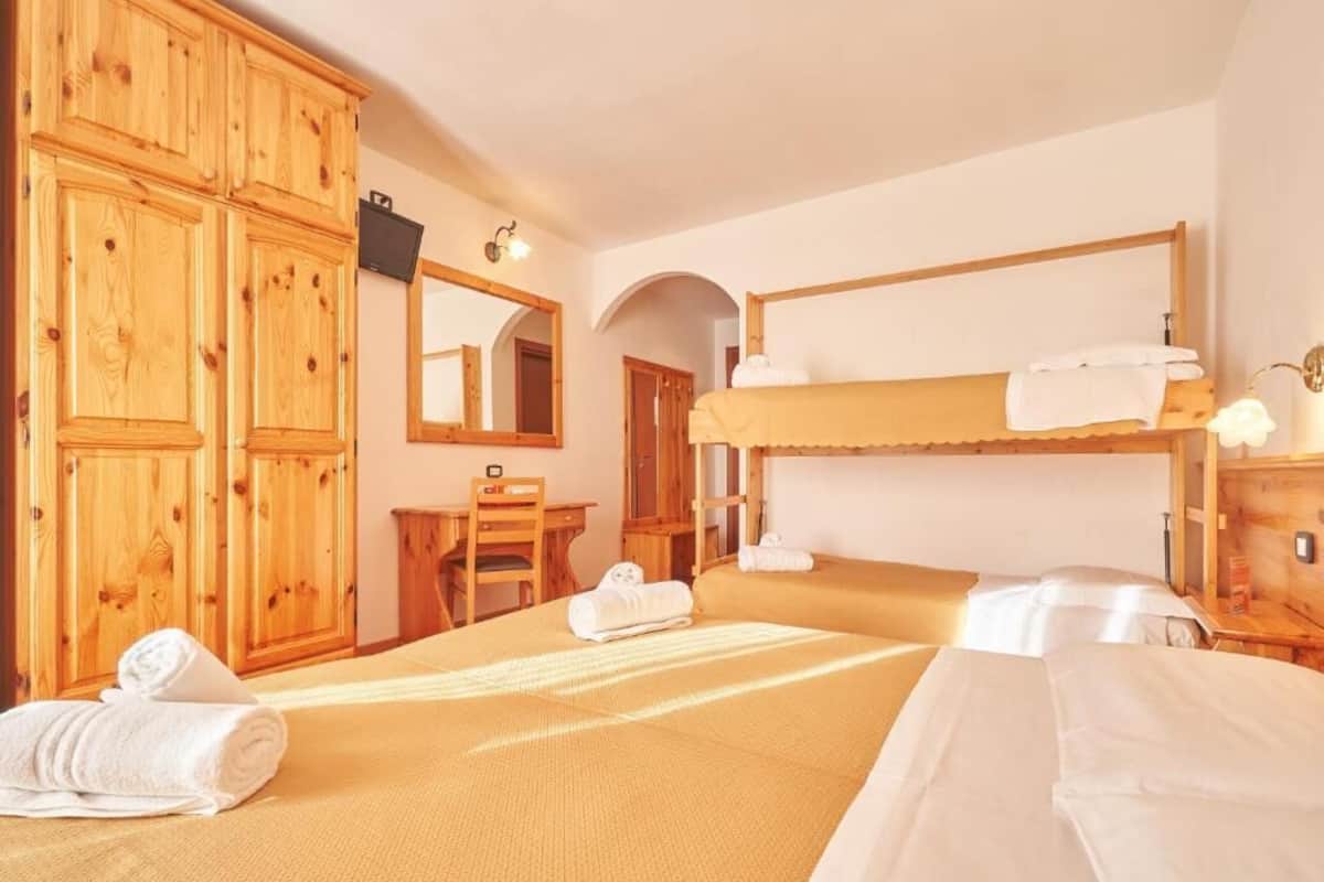 Een kamer met twee bedden, houten kasten, een bureau en een spiegel.