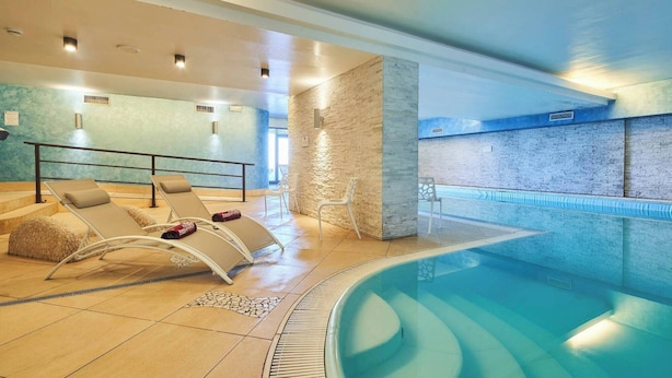 Uma área interna de piscina moderna com espreguiçadeiras e água cristalina.