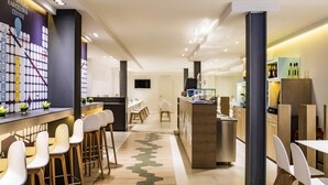Un hall d’hôtel moderne doté d’un bar, de coins salon et d’un comptoir central.