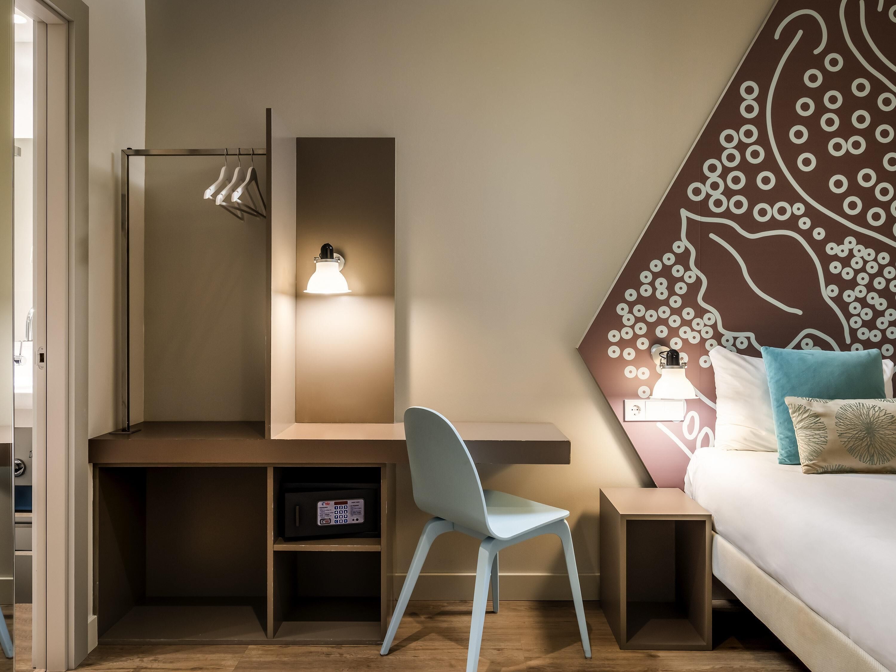 Una habitación de hotel con escritorio, silla, mesita de noche y cama con almohadas.