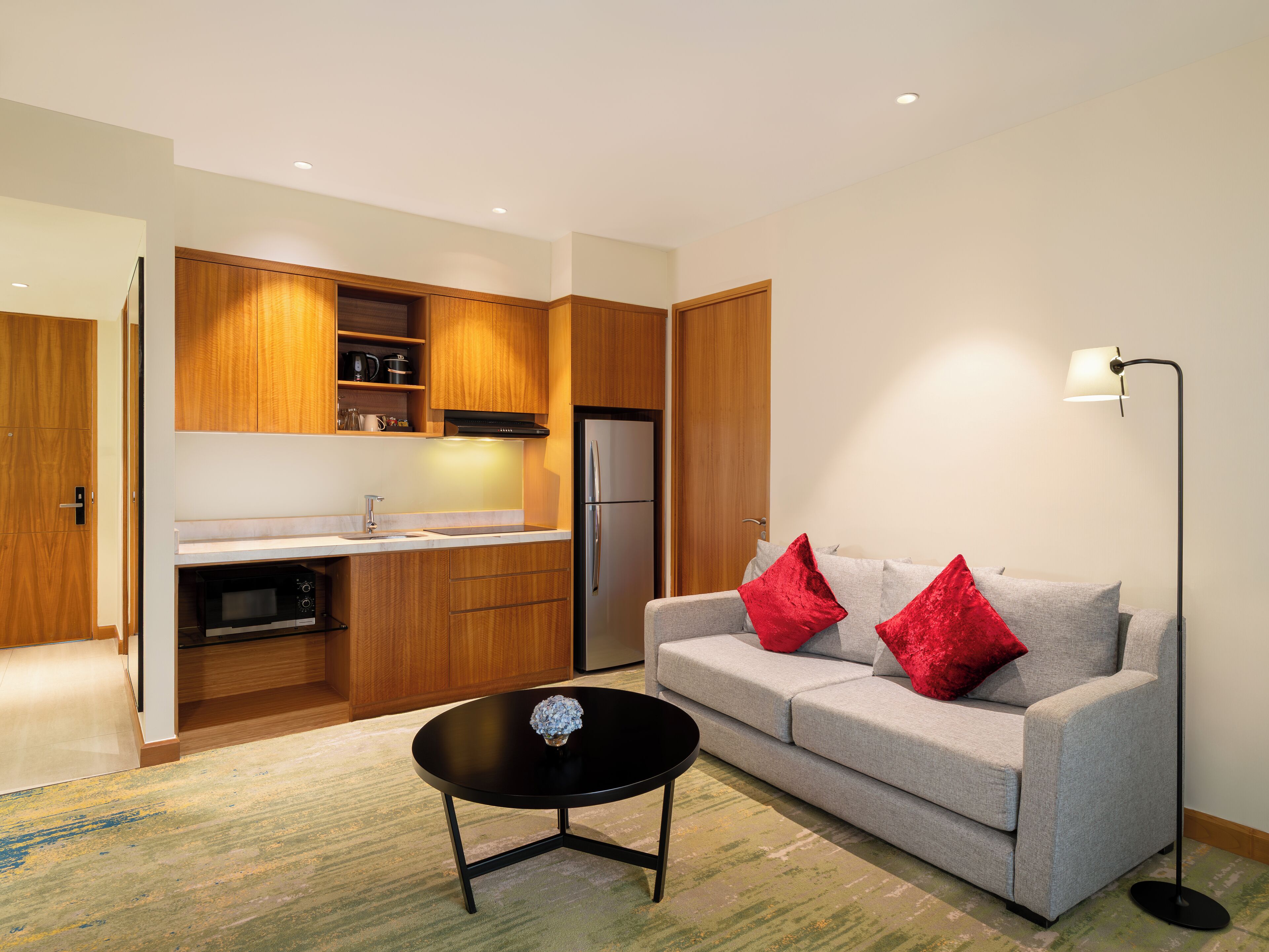A modern living room with a grey sofa, red cushions, a black coffee table, and a floor lamp.