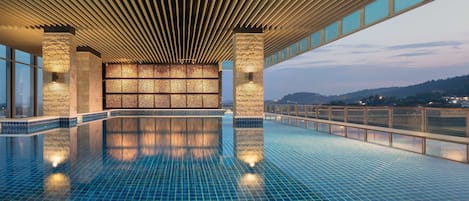 Una piscina cubierta, una piscina al aire libre, sombrillas