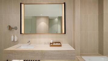 A modern bathroom with a large mirror, two sinks, a bathtub, and a towel rack.