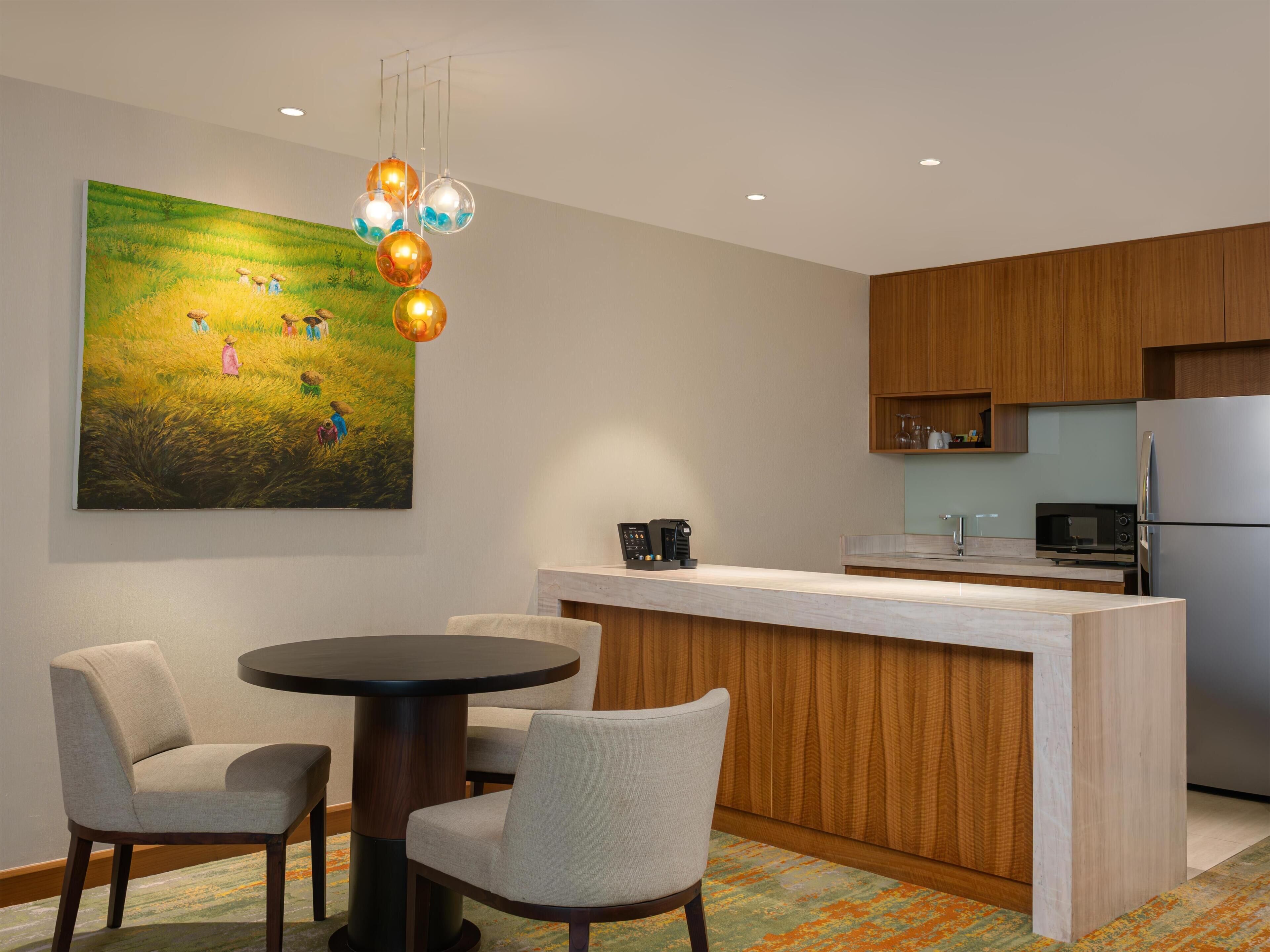 A modern kitchen with a wooden cabinet, a stainless steel refrigerator, a microwave, and a coffee machine on the counter.