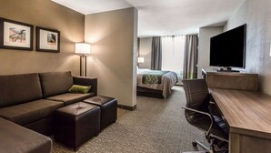 A hotel room with a sofa, a desk, a television, a bed, and a nightstand. - Comfort Inn & Suites Snyder (Snyder)