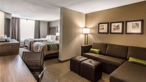 A hotel room with a bed, two bedside tables, a desk, a sofa, and a small ottoman. There are three framed pictures on the wall. - Comfort Inn & Suites Snyder (Snyder)