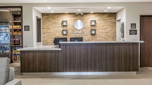 A reception desk with a stone wall backdrop, a check-in counter, and a seating area with a couch. - Comfort Inn & Suites Snyder (Snyder)