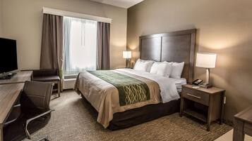 A hotel room with a bed, bedside tables, a desk, a chair, and a television.