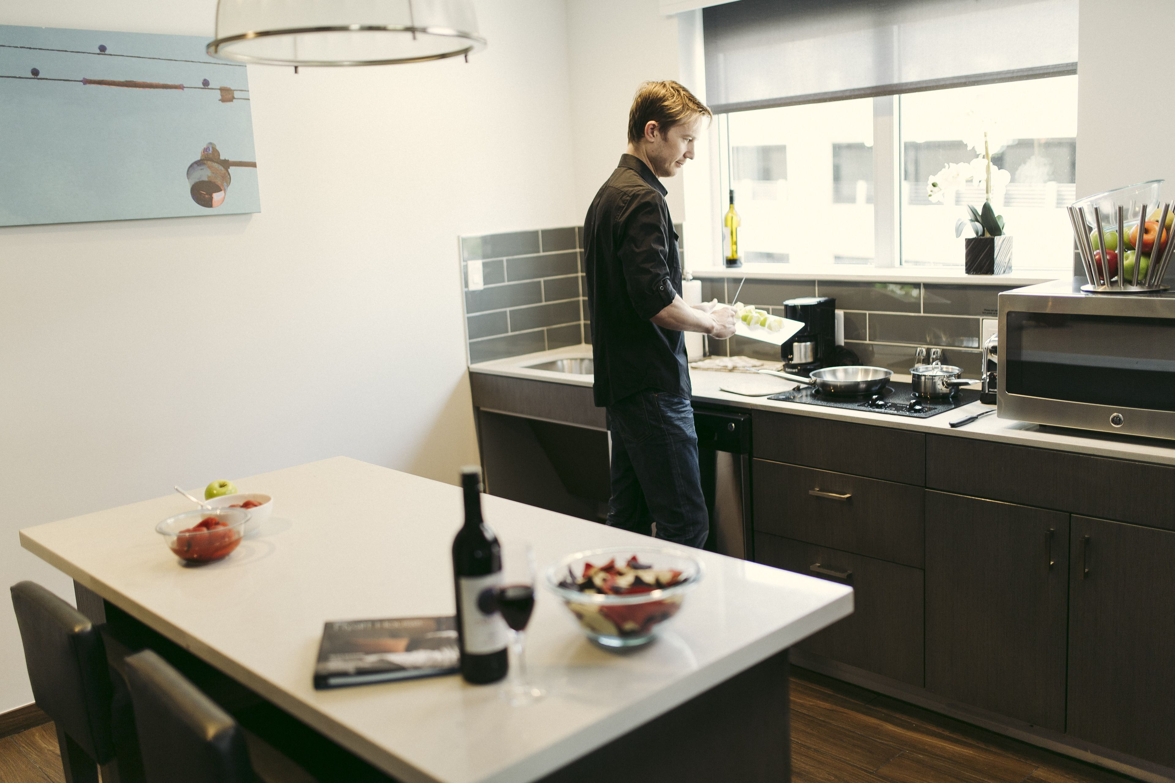 Een moderne keuken met een groot eiland, een raam met uitzicht en diverse keukenapparaten.