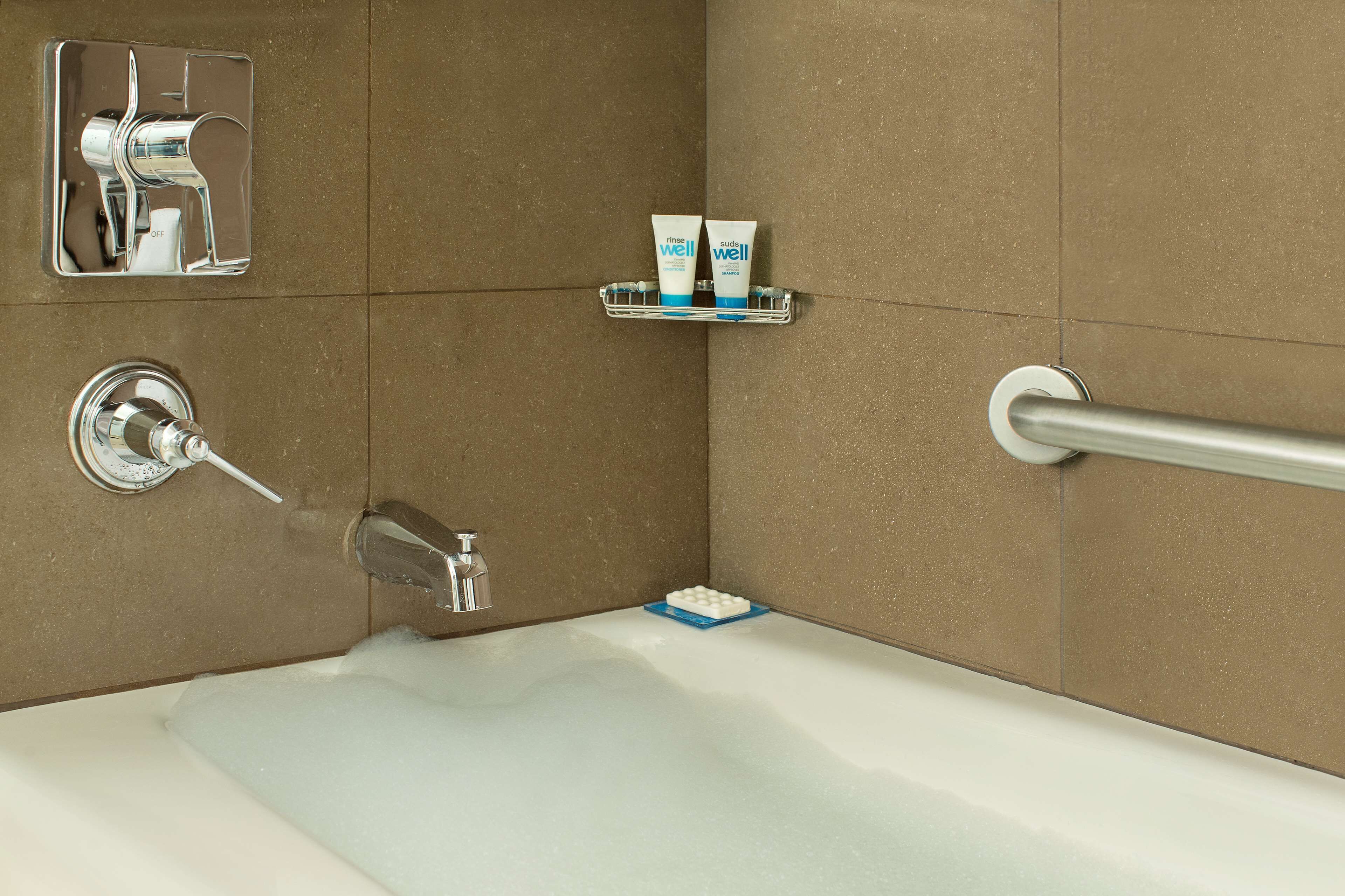 Une salle de bain équipée d’une baignoire, d’une barre d’appui, d’un porte-savon contenant deux savons et d’un robinet.