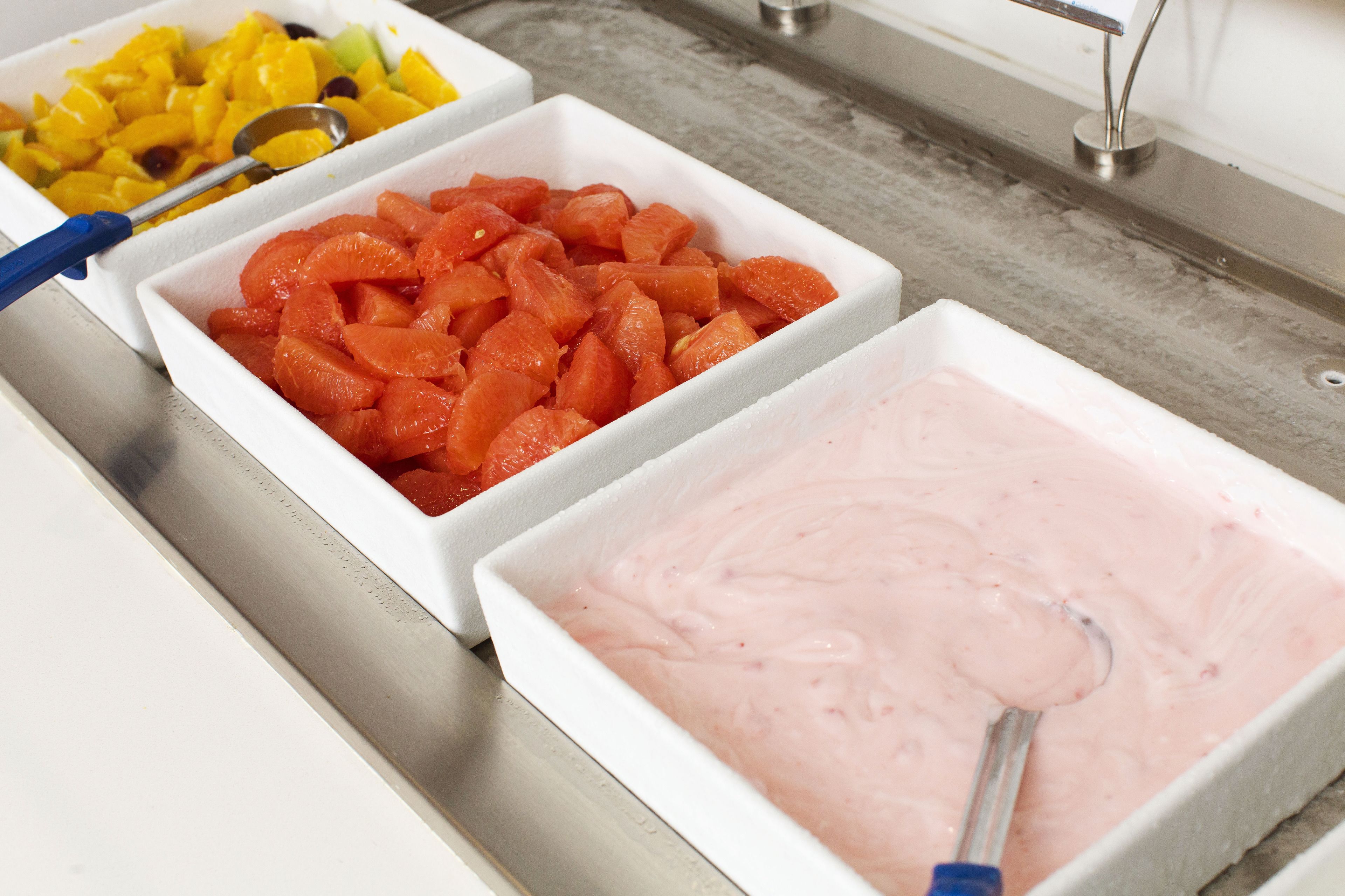 Three white bowls containing diced fruits and a pink mixture, with a metal spoon in each.