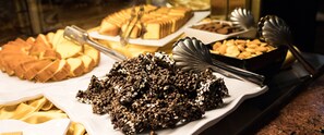 A buffet with various food items including cakes, cookies, and a large pile of what appears to be a grain-based dish. - Gardaland Adventure Hotel (Castelnuovo del Garda)