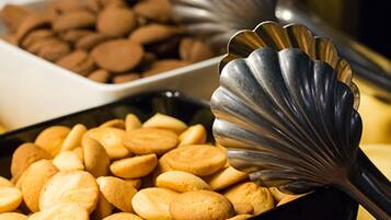 Un buffet proposant une variété de produits de boulangerie, notamment des biscuits et des pâtisseries, ainsi qu'un ustensile pour servir.