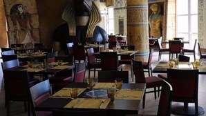 Een restaurant met tafels en stoelen, versierd met oude Egyptische kunst en hiërogliefen.