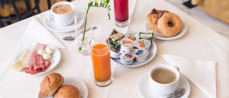 A breakfast table with various food items and drinks, including pastries, cheese, and a glass of orange juice.