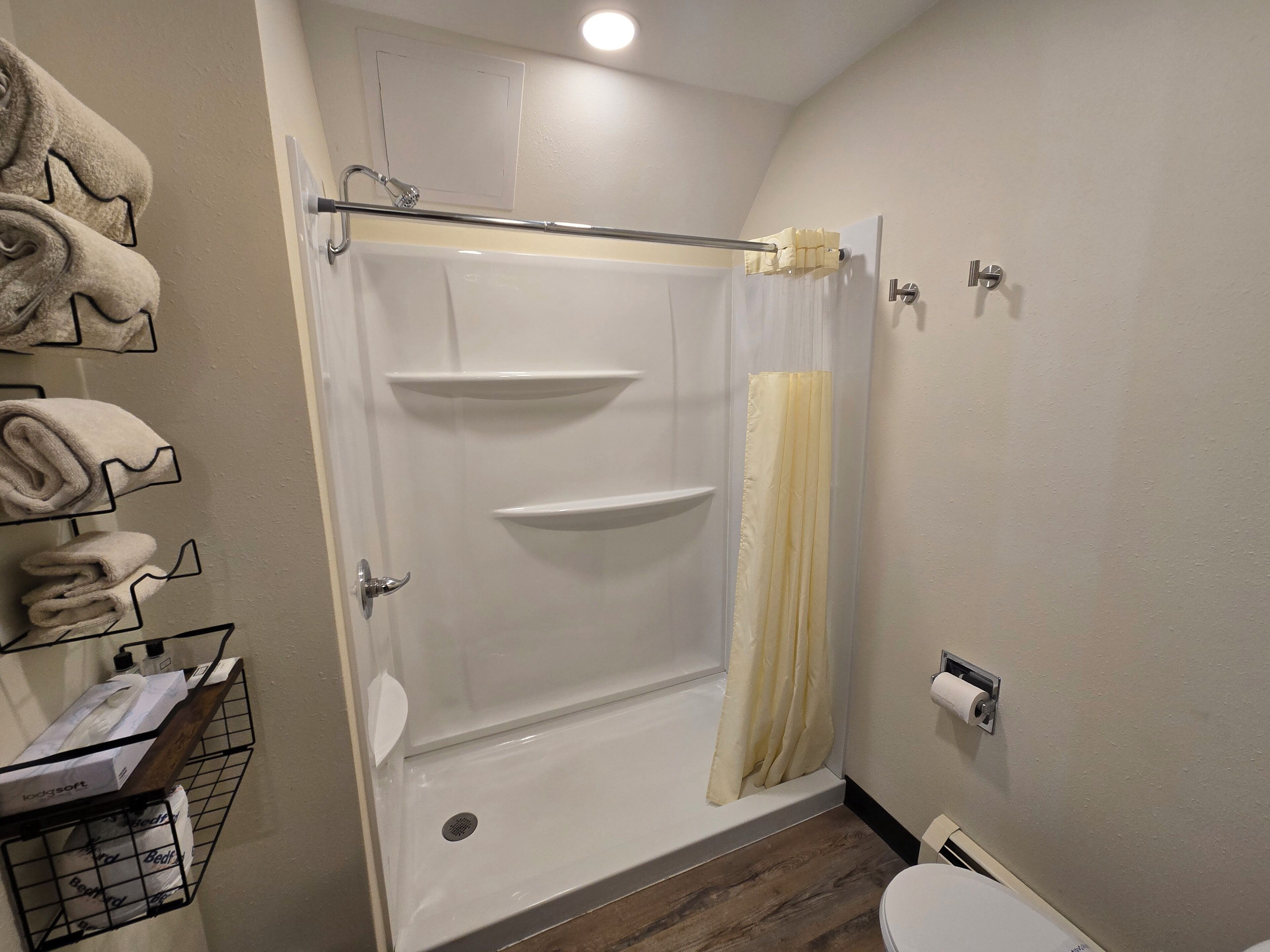 A bathroom with a shower, toilet, and towel rack.